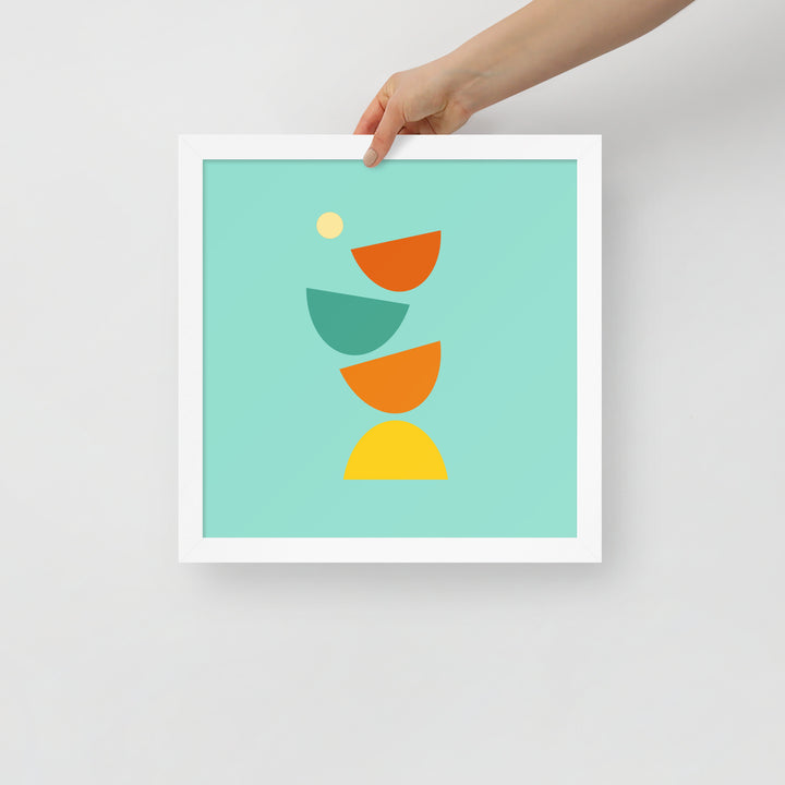 Digital minimalist white framed poster in bright colors with geometric shapes being held in a hand to show size